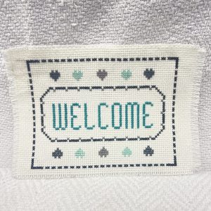 Stitched welcome on cream fabric