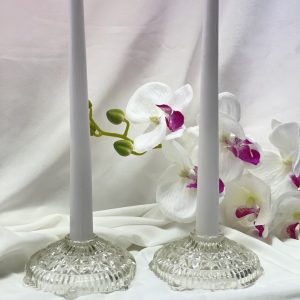 Pair of candles burning in glass base with orchid