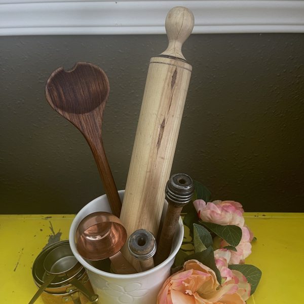 Kitchen utensils in a white pot with pink flowers by it